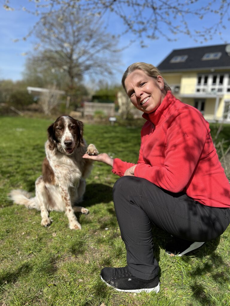 Ein freundlicher Hund gibt der lächelnden Hundetrainerin Kerstin Bahlert sein Pfötchen.